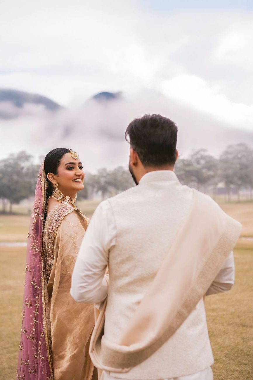 Back view of the couple with low mist rolling over the hills behind them