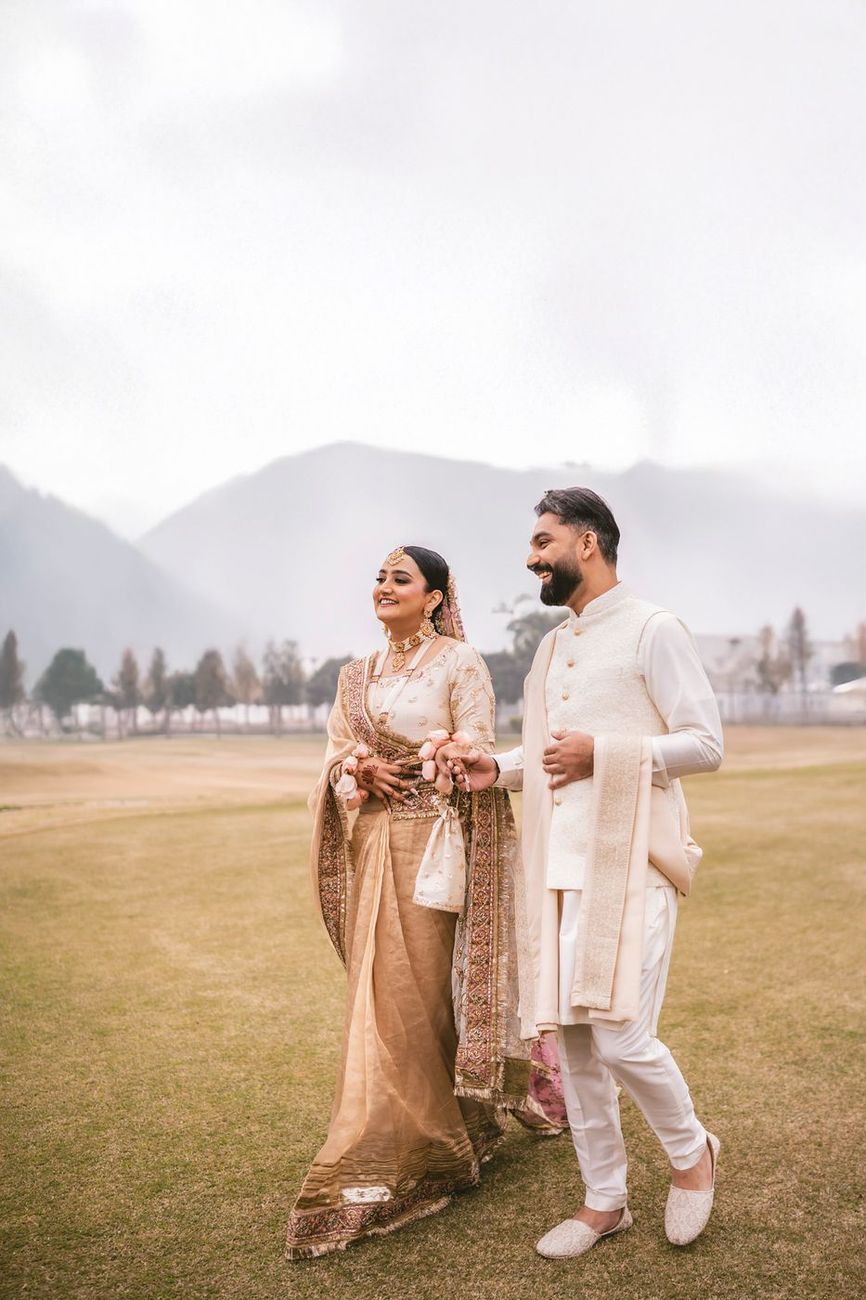 Couple walking and laughing across the misty field, mountains behind them