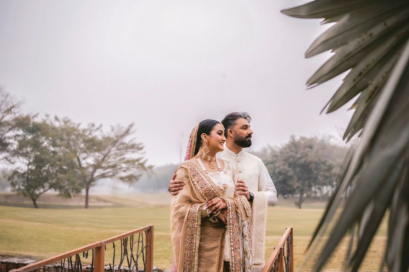 Couple standing on the bridge looking off into the distance together