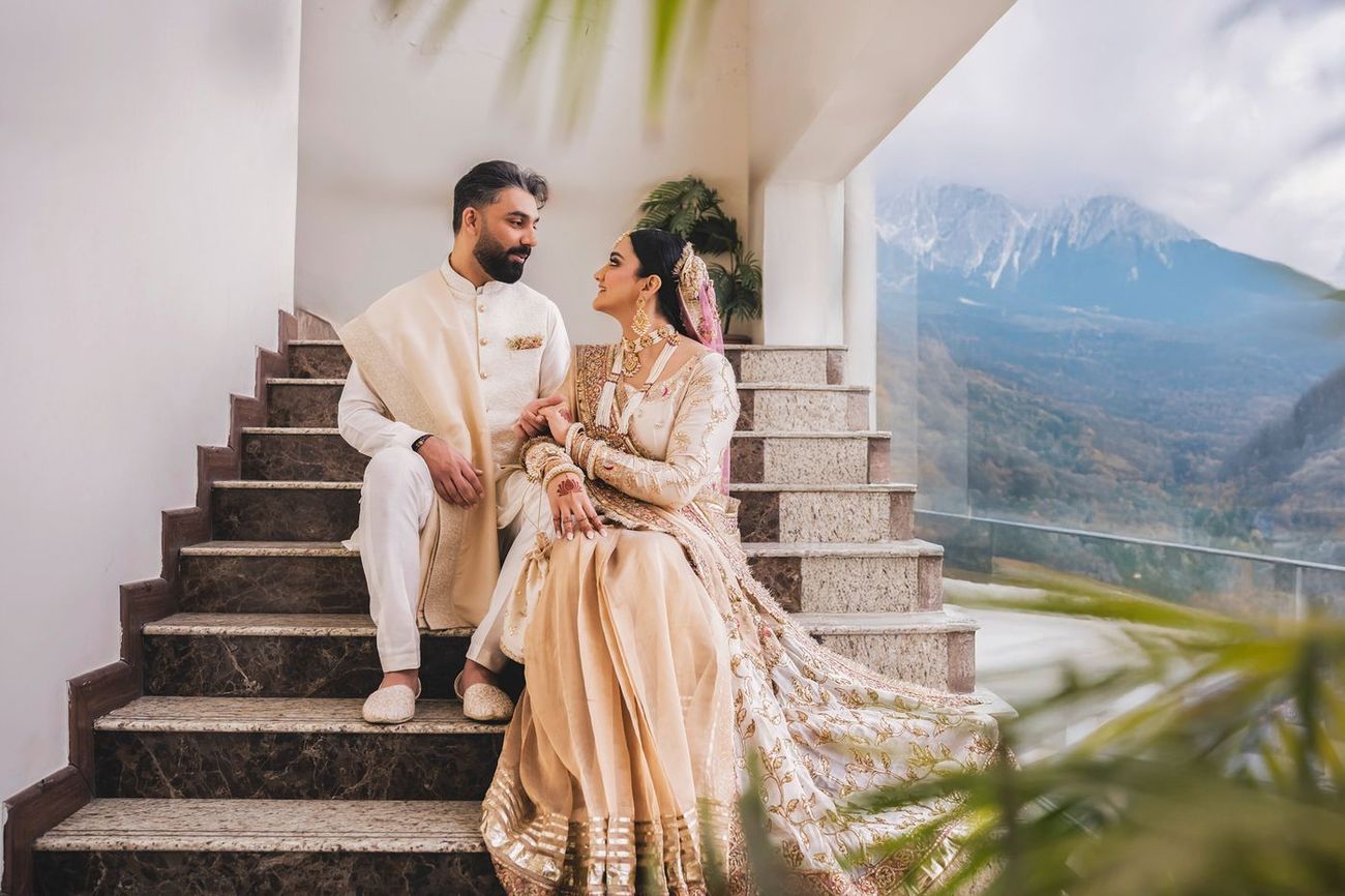 Couple seated together on a marble staircase with a sweeping mountain valley view