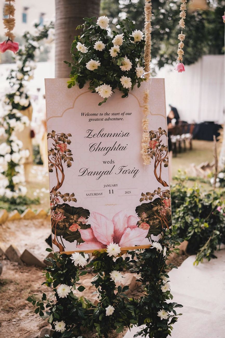 Welcome signage for Zebunnisa and Danyal's wedding, decorated with white and pink flowers