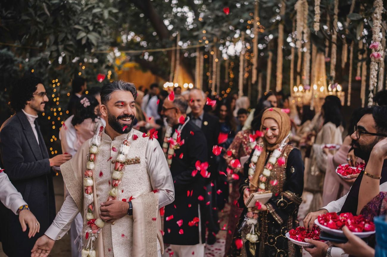 Rose petals showered over the groom as guests walk through the festive welcome procession