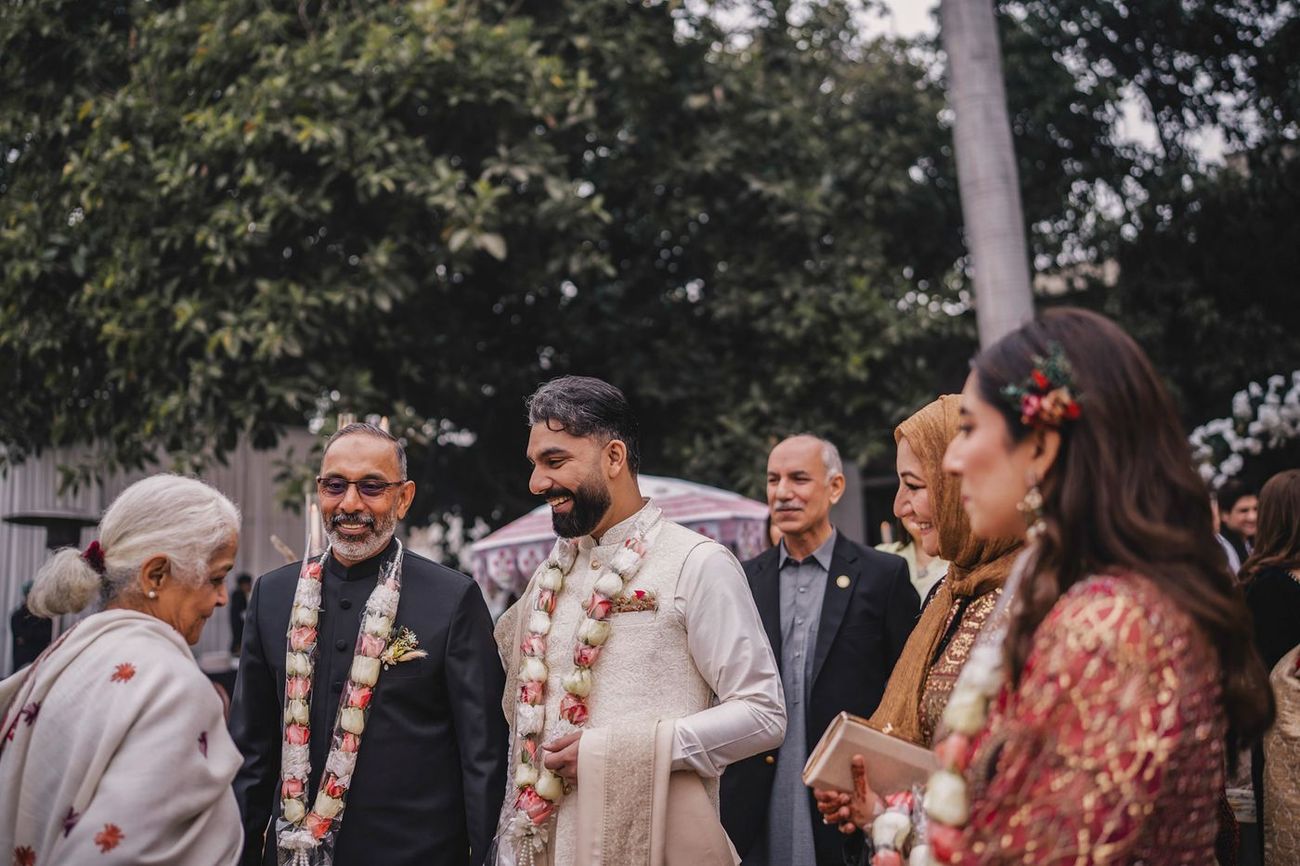 Groom in floral garlands chatting with elderly family members and guests