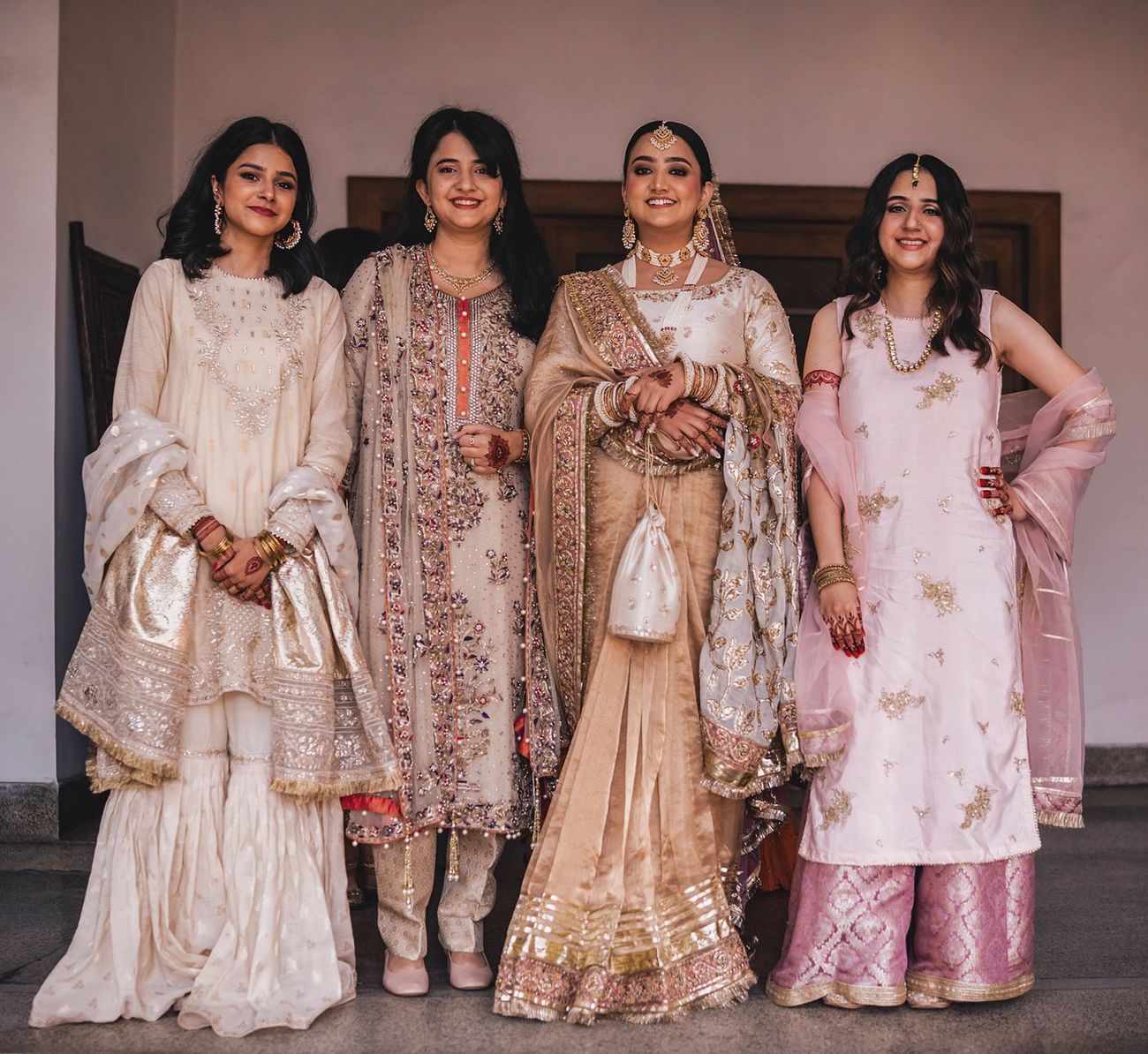 Bride posed with three female friends, indoor archway backdrop