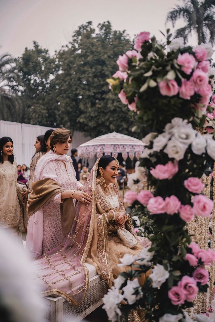 Bride seated on the ceremony bench, framed by pink and white roses