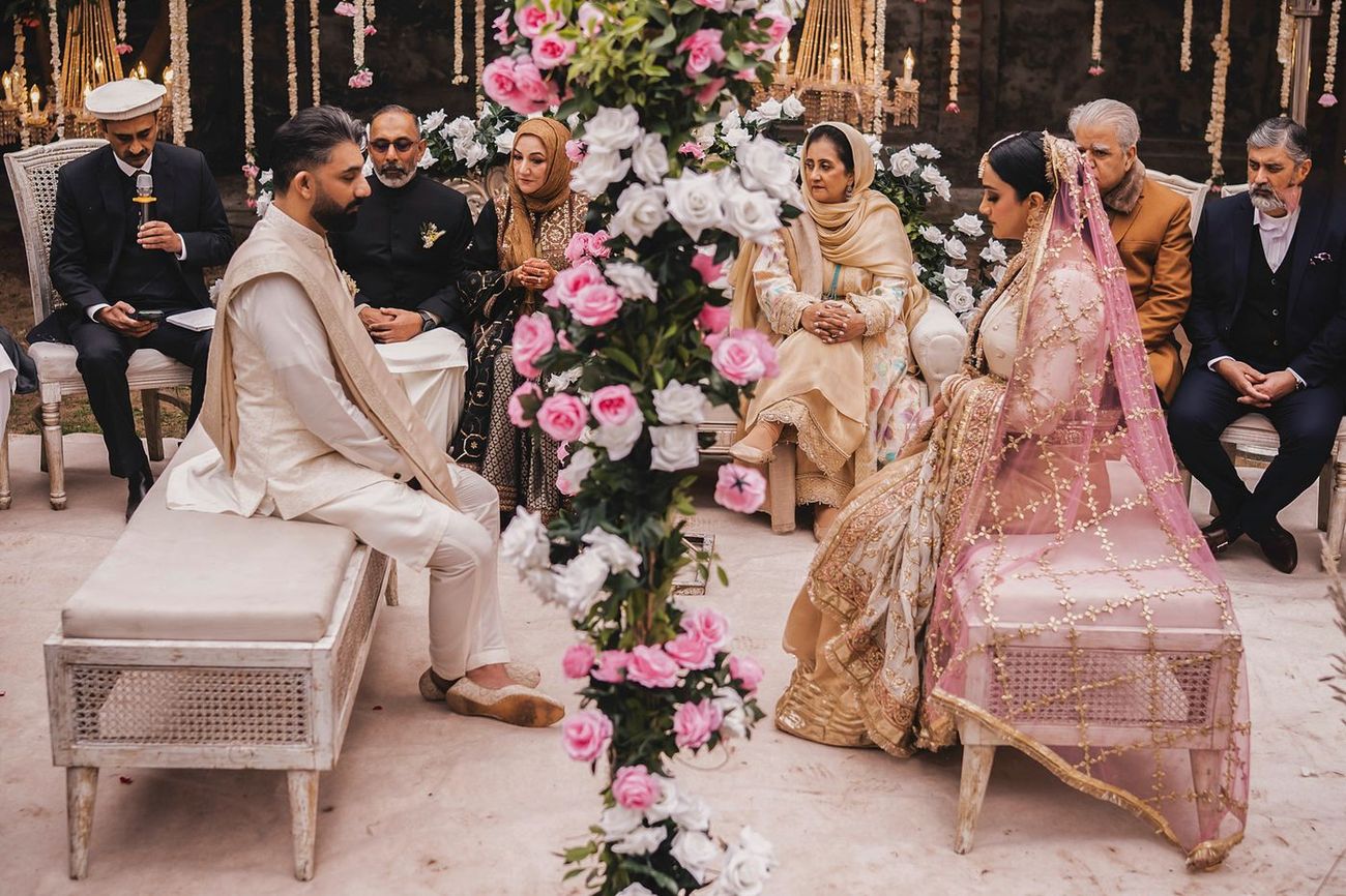 Wide nikah ceremony shot with both families seated around the floral divider