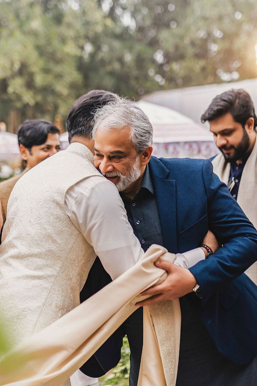 Groom embraced warmly by an older male relative outdoors