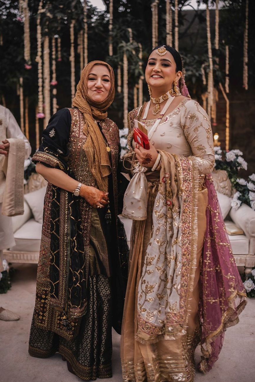 Bride posed together with the groom's mother, both smiling for the camera