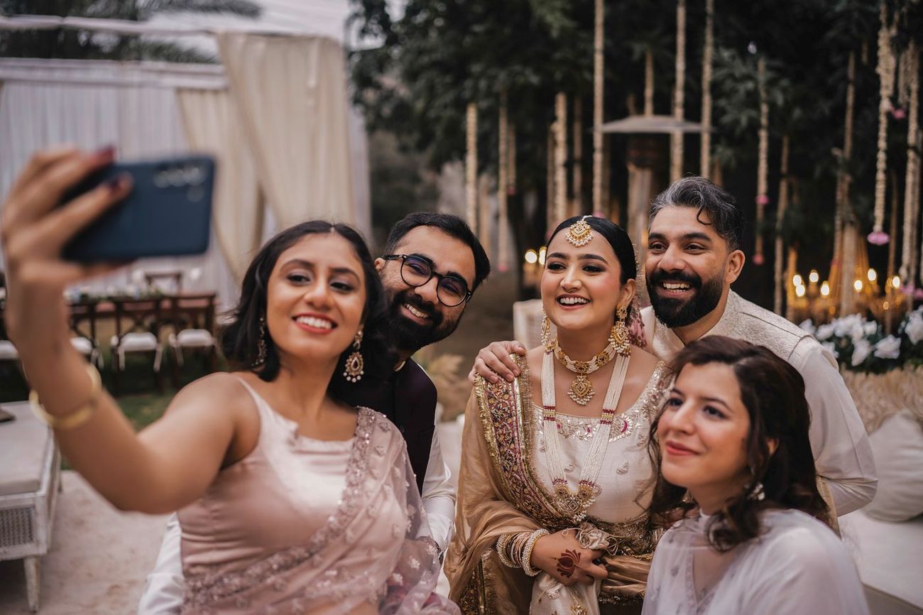 Bride and groom taking a candid group selfie with friends