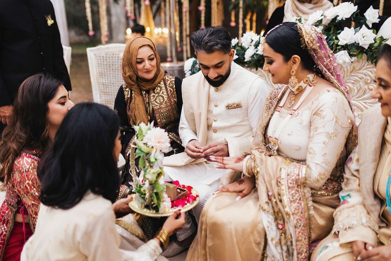 Couple seated together as an attendant brings the ring tray, family members around them