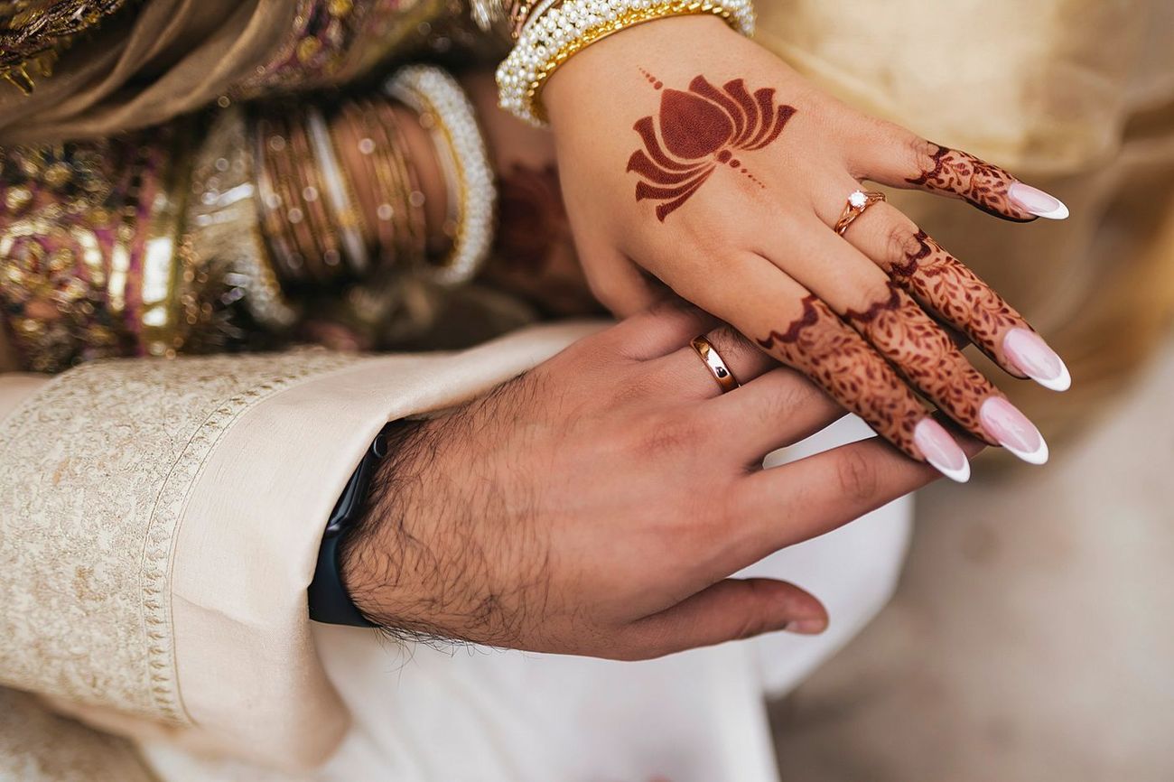 Close-up of the couple's stacked hands, both wearing their new wedding rings