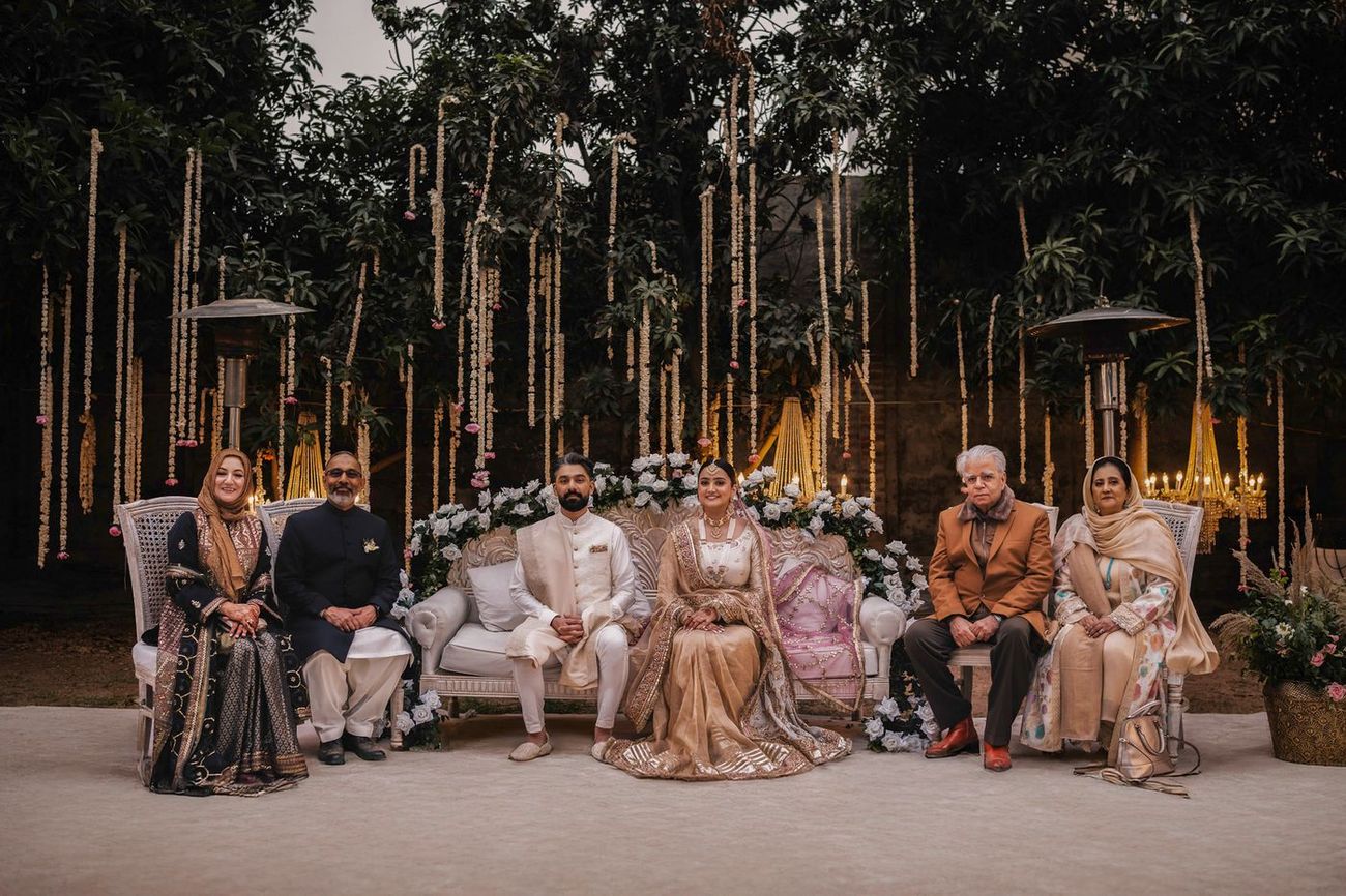 Wide family portrait, couple seated centrally with both sets of parents flanking them