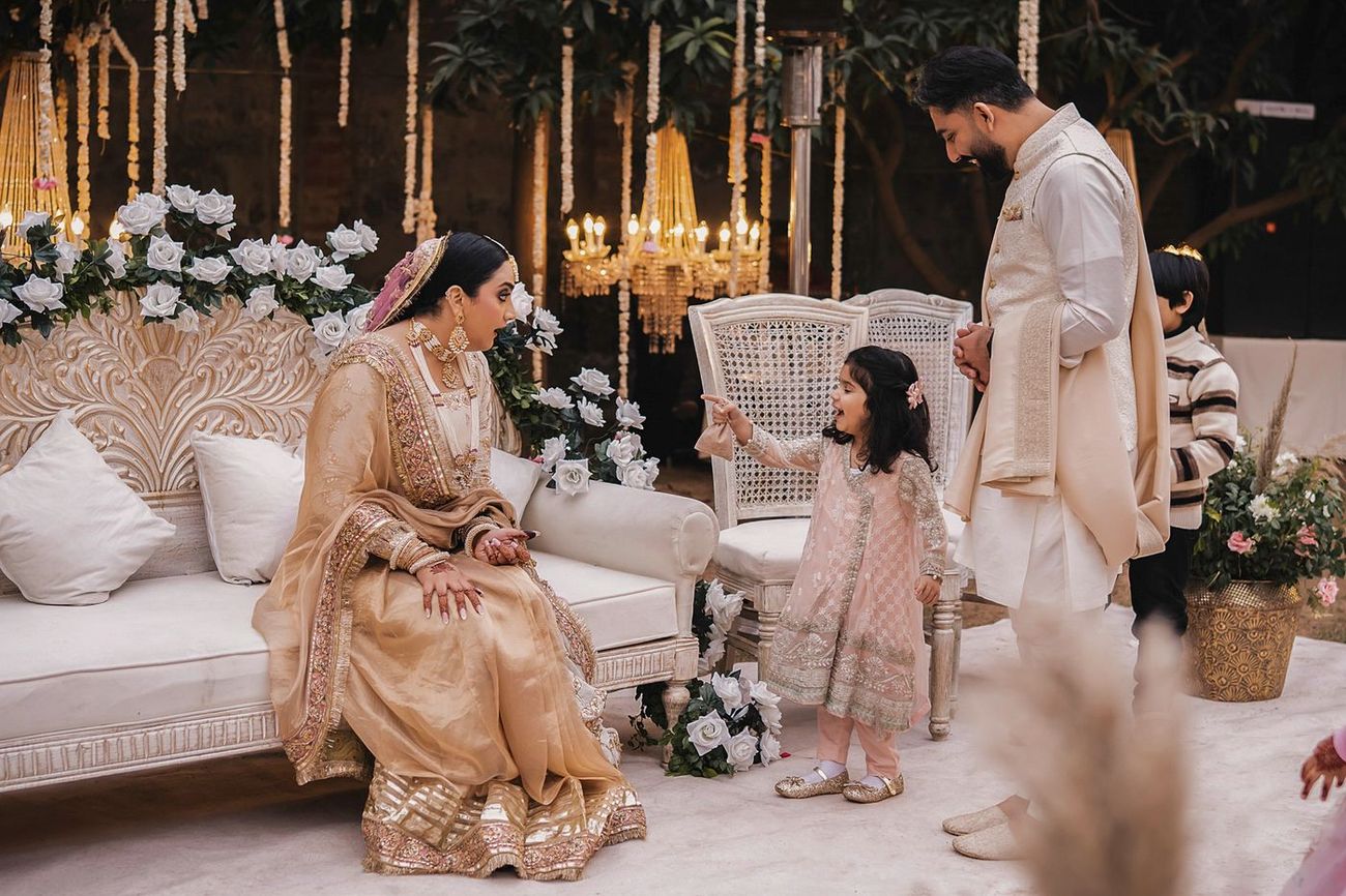 Sweet candid moment of a young girl chatting with the bride and groom on the decorated stage