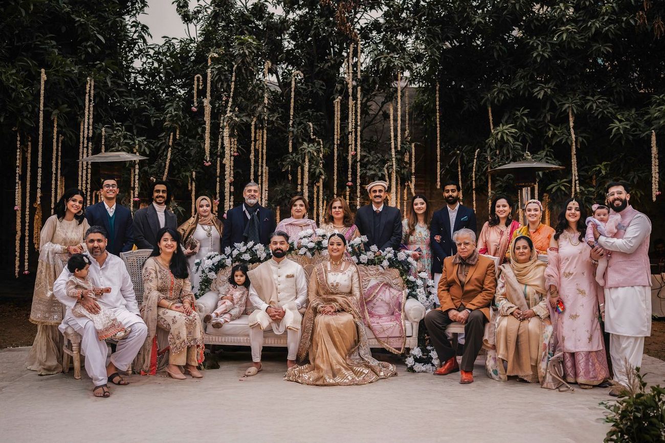Large full family group portrait with the couple seated centrally among extended family and children
