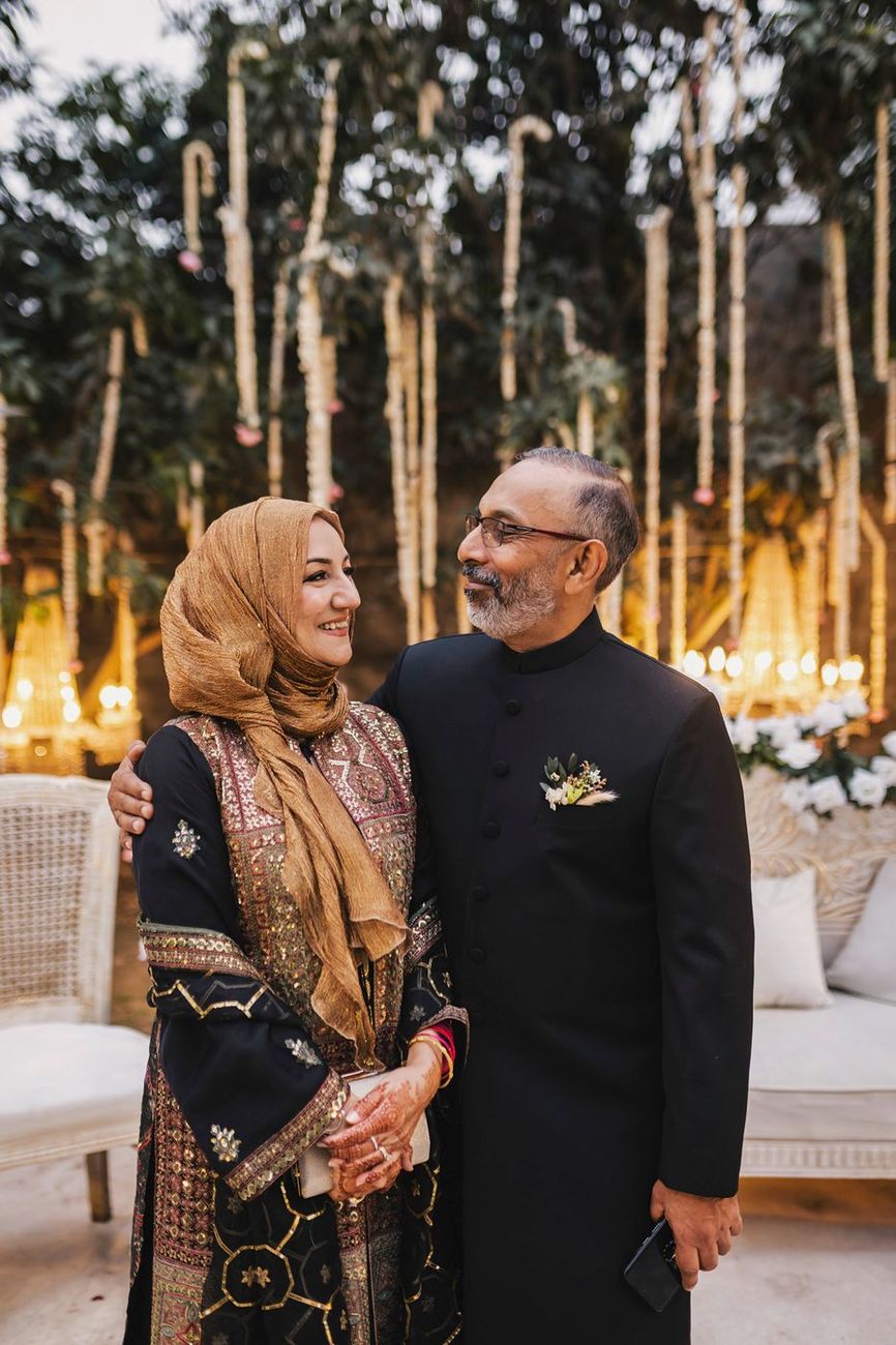Groom's parents posed together affectionately on the lit stage