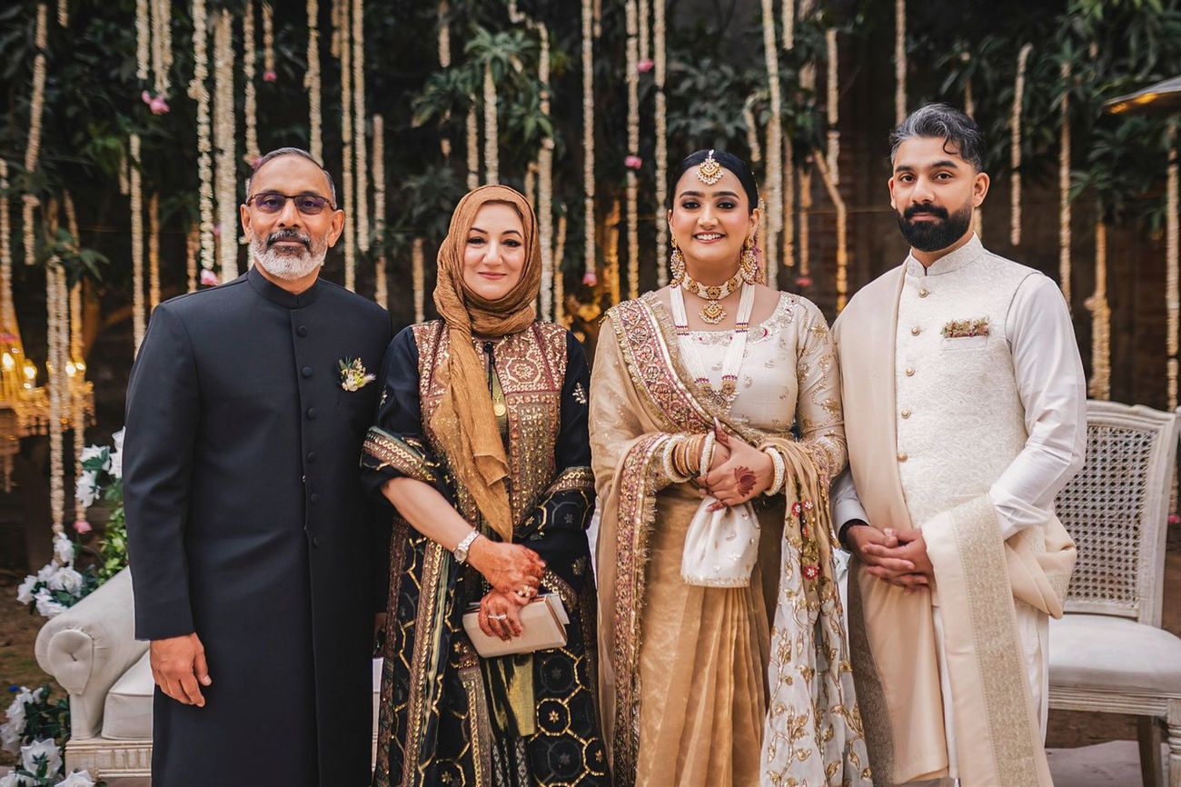 Couple posed standing with the groom's parents, formal four-person portrait