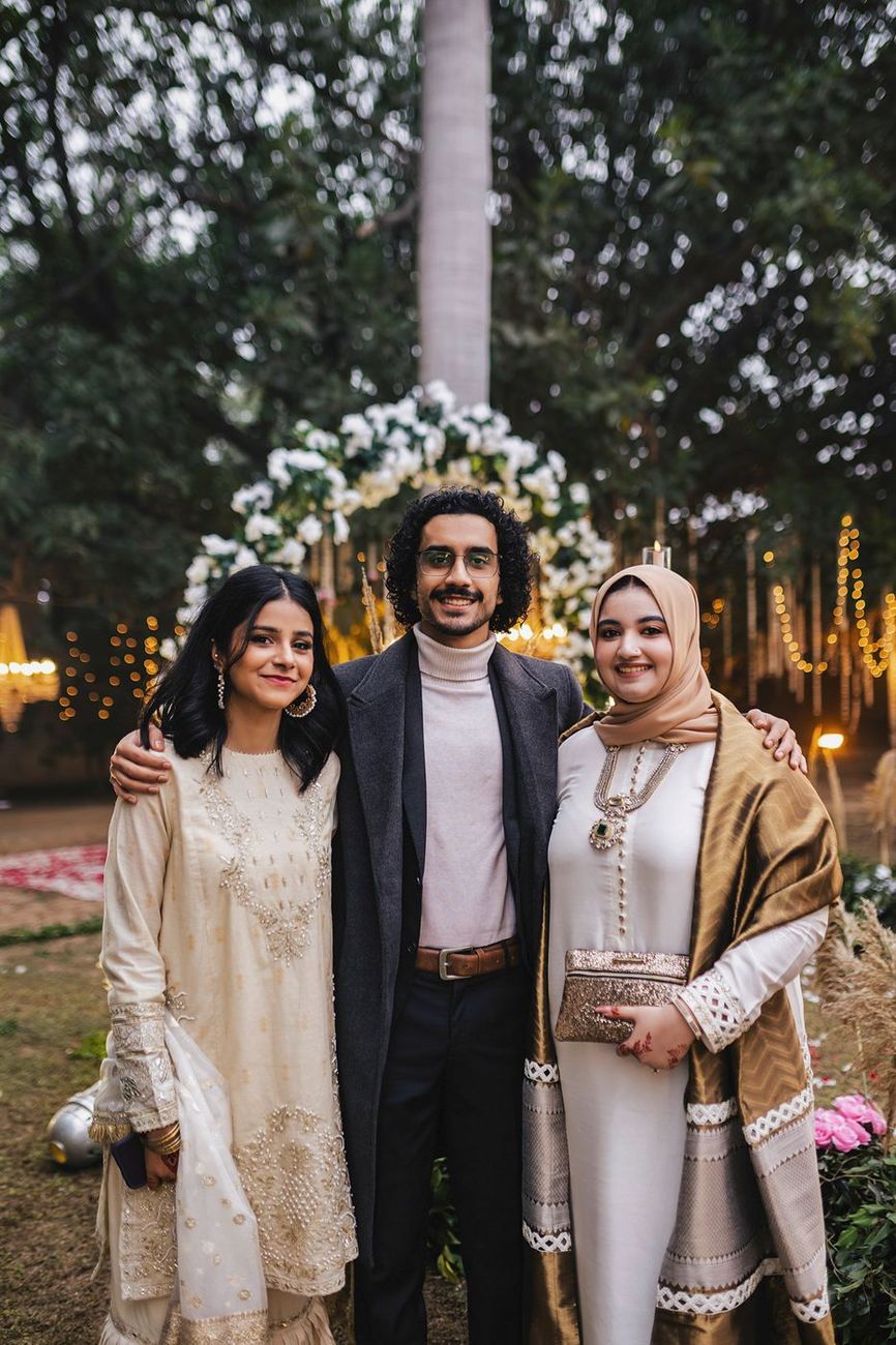 Three guests posed together at the same floral arch