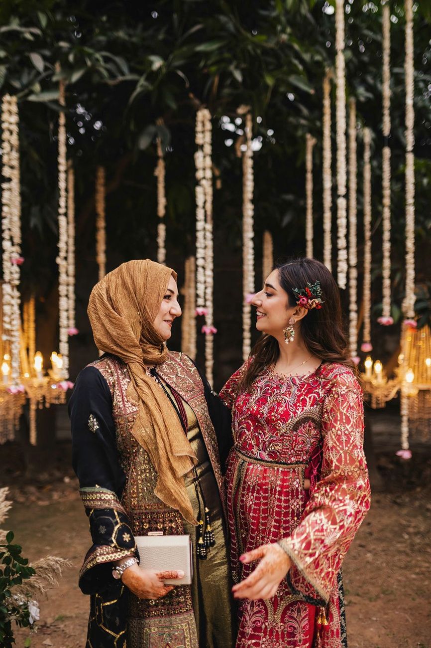 Groom's mother chatting with another woman in a red embellished outfit