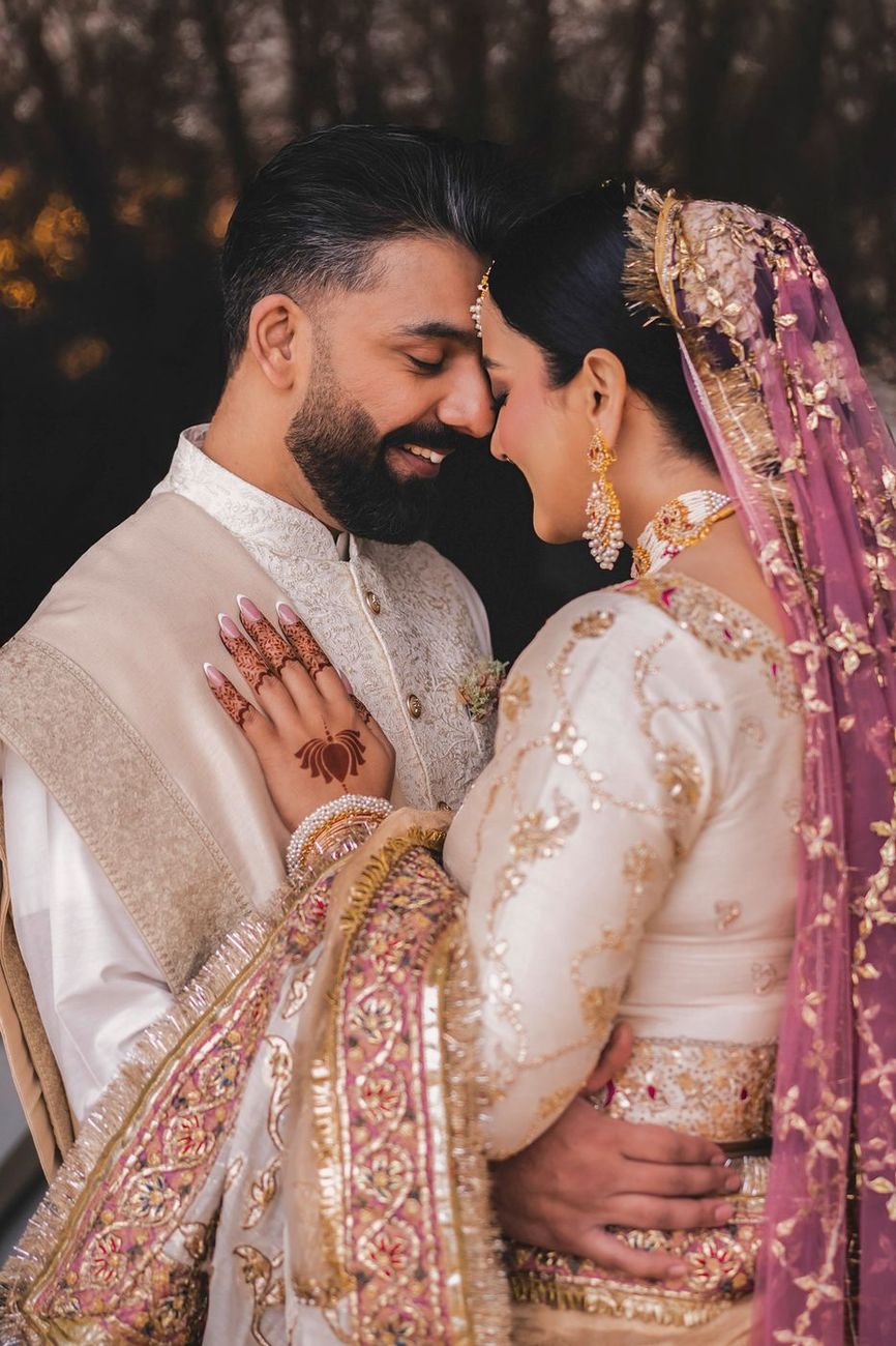 Bride and groom in a forehead-to-forehead embrace, evening light, her pink and gold dupatta visible