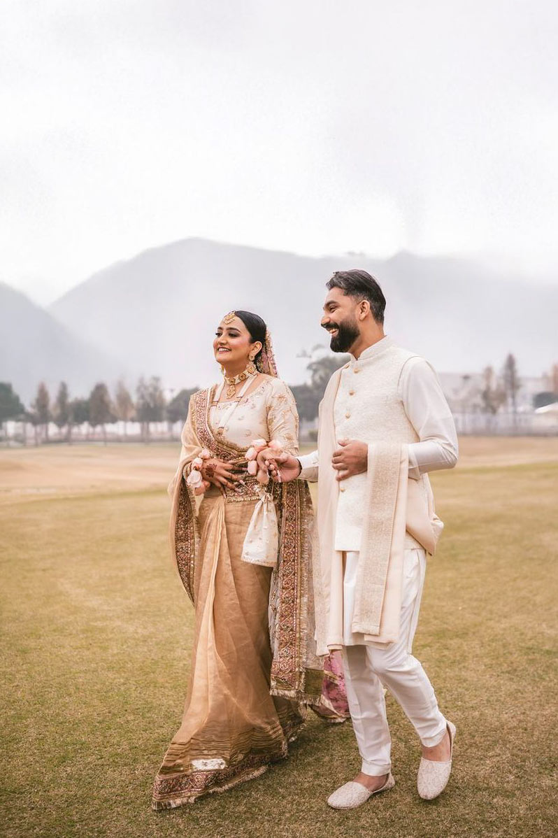 Bride and groom laughing together in a misty outdoor setting, bride's henna-painted hand resting on his shoulder, Zebunnisa & Danyal's wedding, Lahore